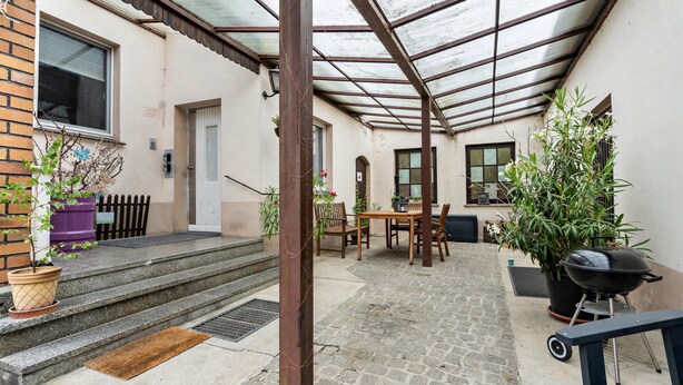 A covered patio with steps leading to a door, a table and chairs, a grill, and potted plants. - Holiday Apartment "Am Wald Dachgeschoss" with Shared Terraces, Shared Garden & Wi-Fi (Krauschwitz)