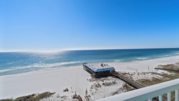 A beach view with a wooden boardwalk leading to a building with a blue roof. - Book Boardwalk 783 – Breathtaking Gulf Views Await! (Gulf Shores)