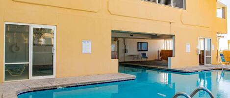 Una piscina con una escalera metálica, un área techada con mesa y sillas, y un cartel que indica las normas de la piscina.