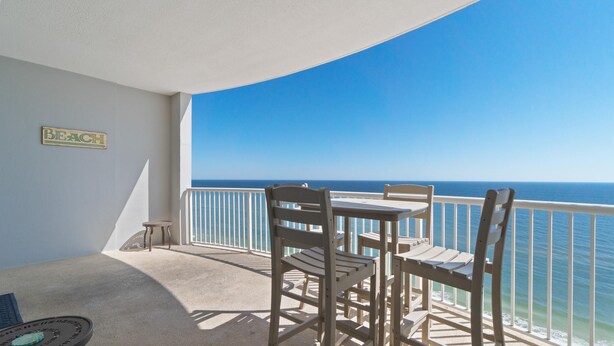 Un balcón con mesa y sillas, una mesita pequeña y un letrero que dice "BEACH".