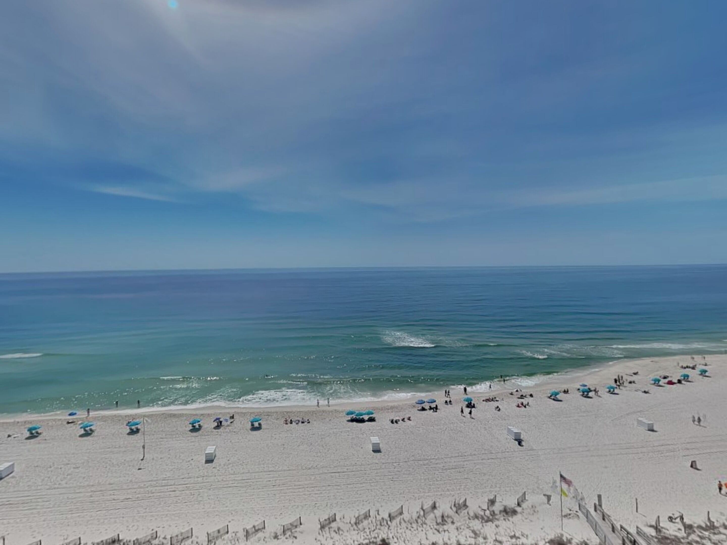 A beach with umbrellas and sun loungers, a sandy shore, and the ocean.