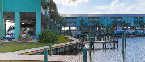 Een jachthaven met aangemeerde boten, een groen gebouw met balkons en een houten steiger.