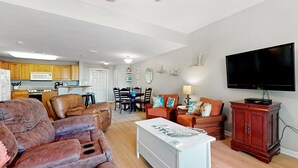 Amplia sala de estar con sofá, televisor y mesa de comedor con sillas.