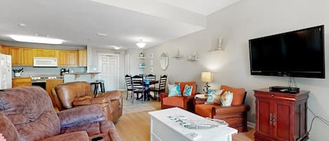 A spacious living area with a sofa, a TV, and a dining table with chairs.