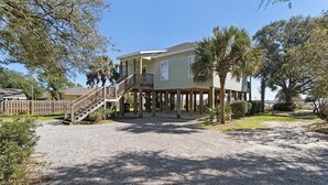 A two-story house with a covered porch and a wooden staircase leading to a balcony. - Private Pool – Perdido Bay Views – Pet-Friendly Escape! (Elberta)