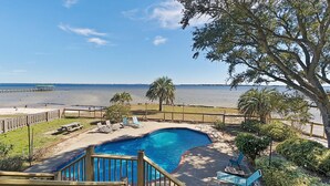 A swimming pool with a wooden deck, lounge chairs, and a view of the beach and ocean. - Private Pool – Perdido Bay Views – Pet-Friendly Escape! (Elberta)