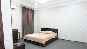 A bedroom with a bed, a television, and a desk. - Zamona Hotel (Tashkent)