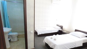 A hotel room with two beds, a toilet, and a shower area. - Zamona Hotel (Tashkent)