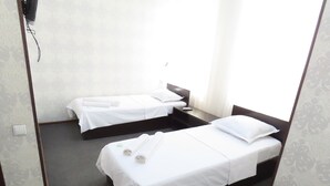A hotel room with two single beds, a small table, and a chair. - Zamona Hotel (Tashkent)