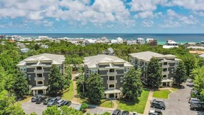 A residential area with three-story buildings, a parking lot, and a view of the ocean.