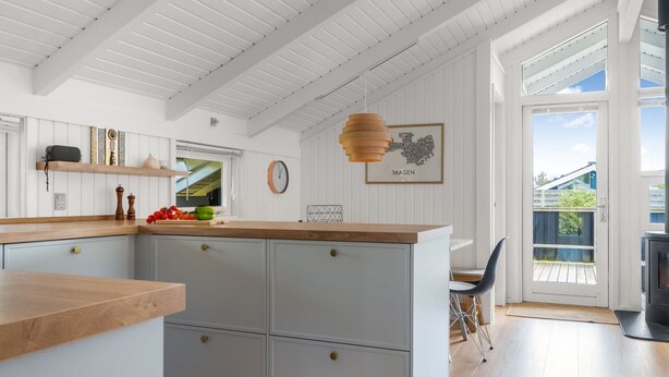 Une cuisine moderne avec des meubles blancs, un plan de travail en bois et un luminaire suspendu.