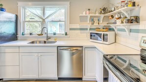 A modern kitchen with white cabinetry, a dishwasher, a microwave, and a stove. - 1 Mi to Beach: Sustainable Oak Island Home! (Oak Island)