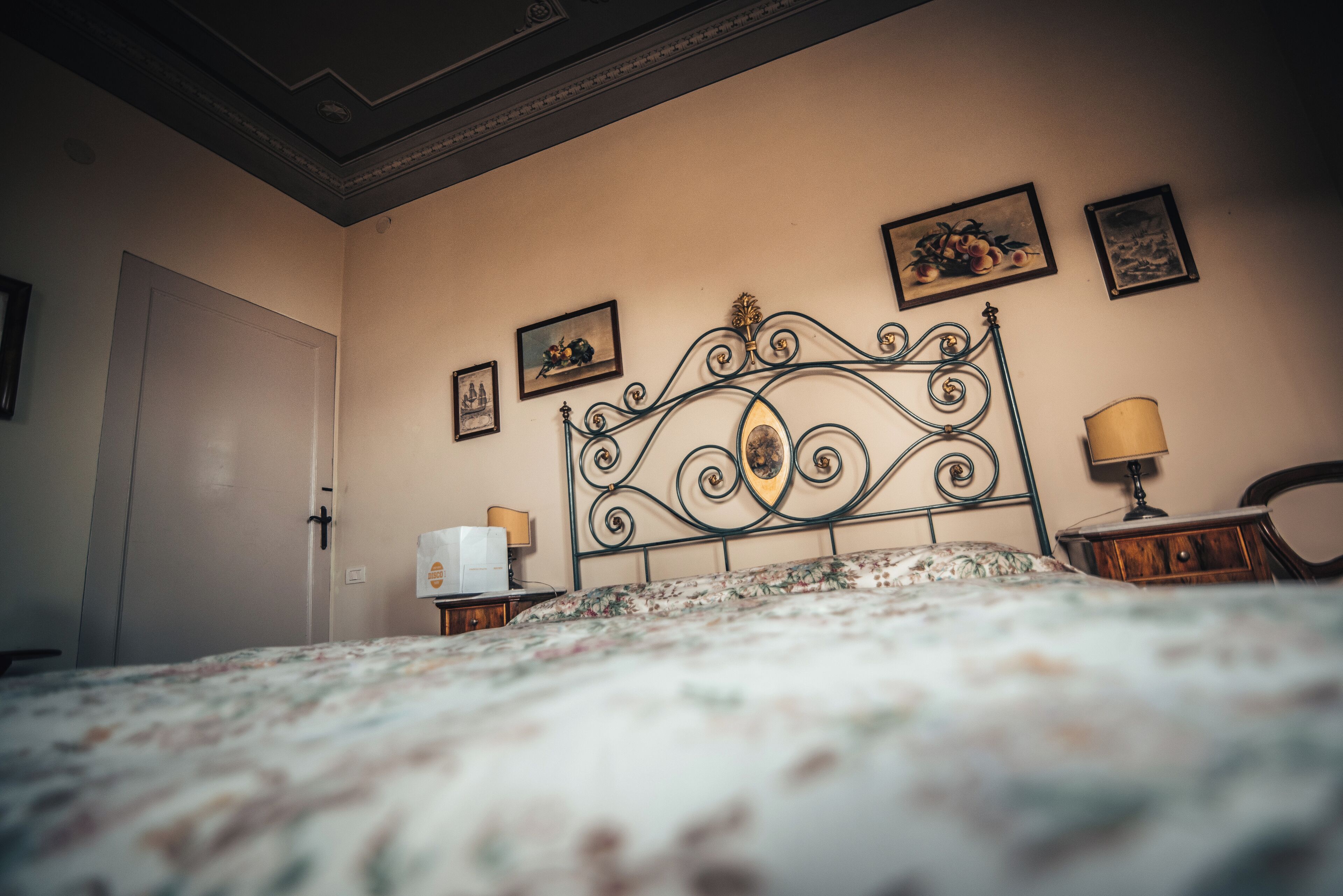 A bedroom with a bed, a nightstand, a lamp, and framed pictures on the wall.