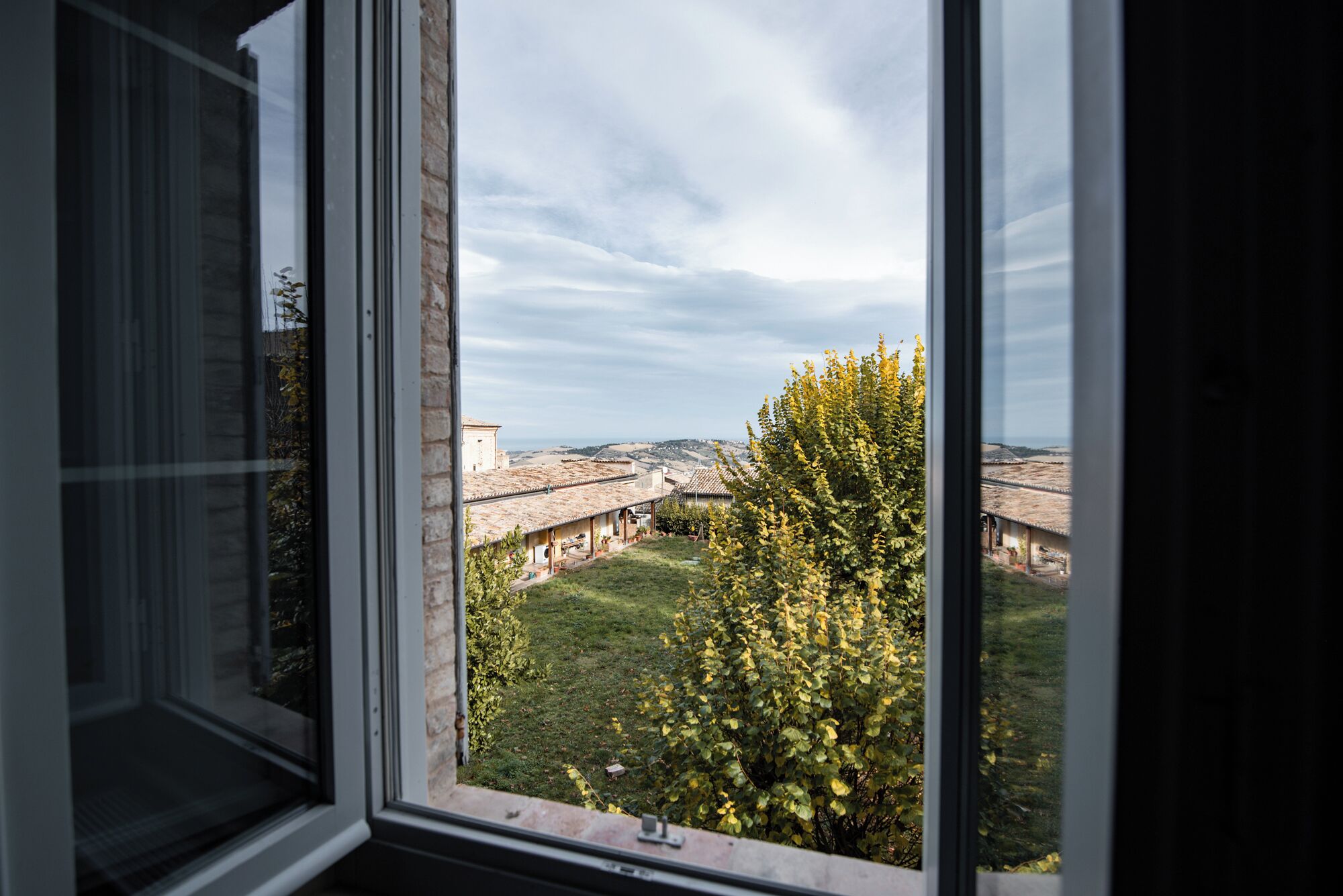 Une vue depuis une fenêtre donnant sur une cour, avec un bâtiment en arrière-plan.