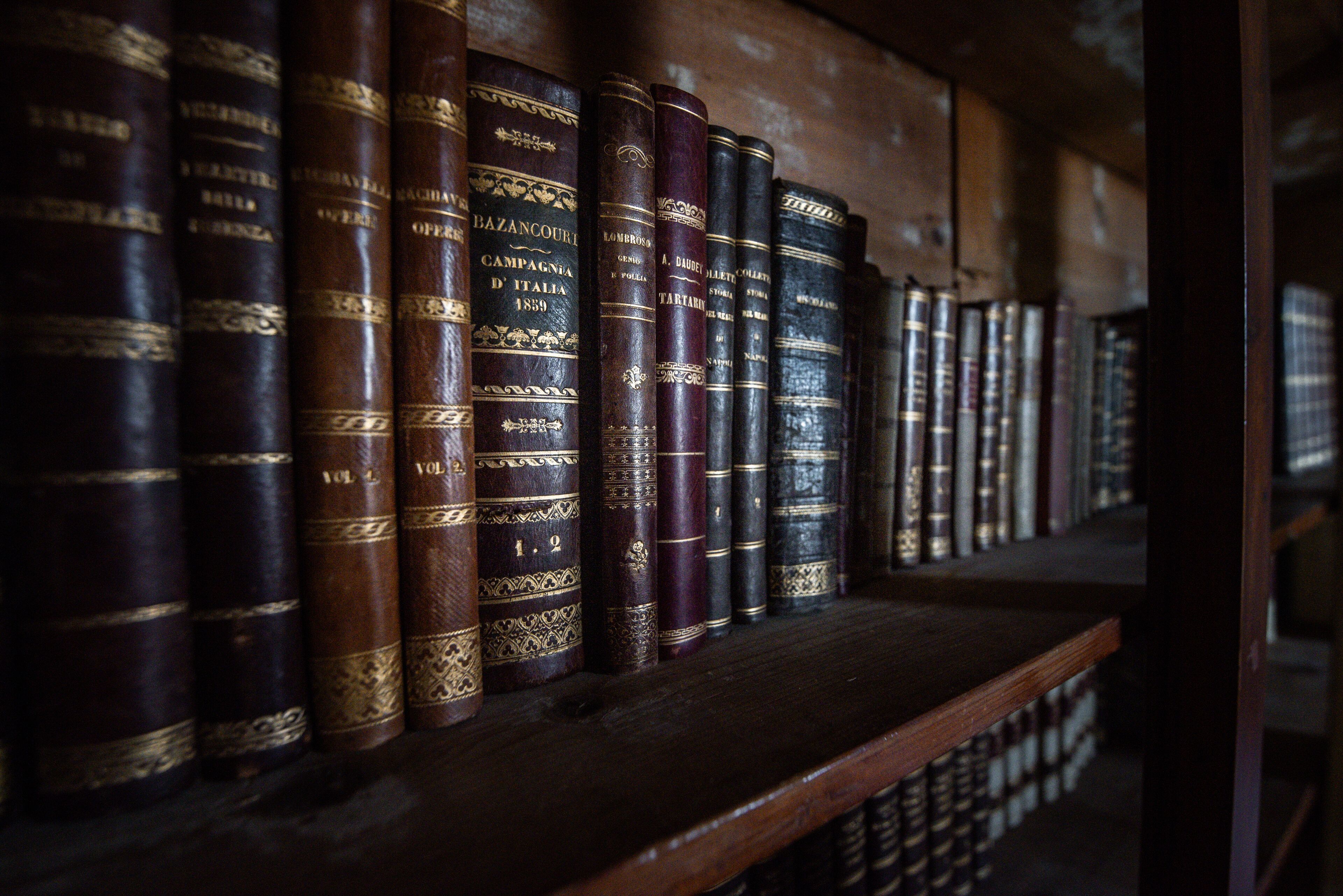 Una estantería con libros encuadernados en cuero, algunos con detalles dorados.