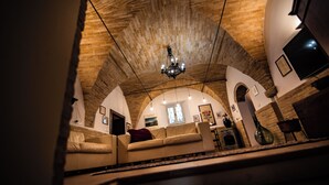 Ein gemütliches Wohnzimmer mit einer gewölbten Decke, einem Chandelier und einem Kamin.