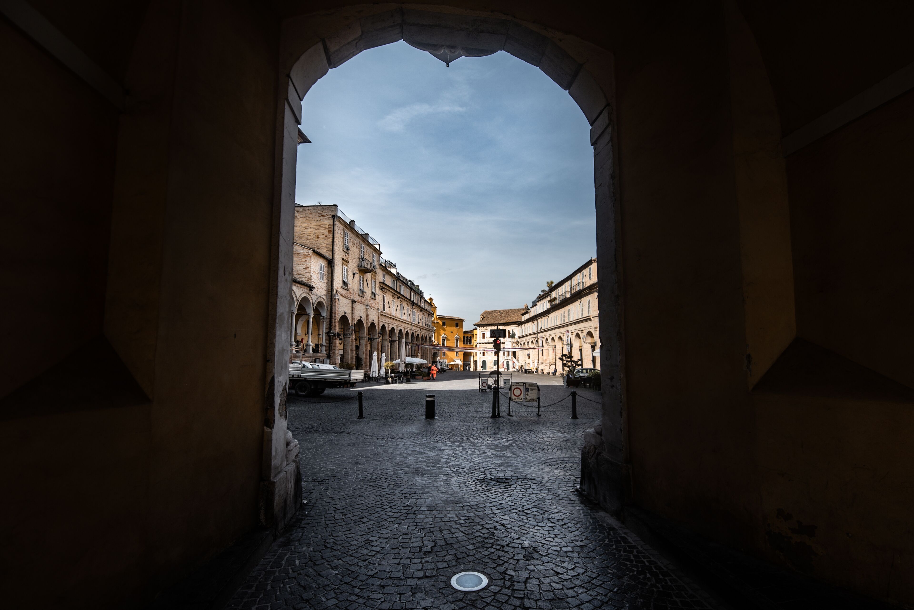 Una entrada en arco que conduce a una calle adoquinada con edificios históricos.