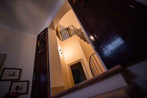 Una escalera con barandilla de madera y baranda de metal que lleva a un rellano con una puerta.