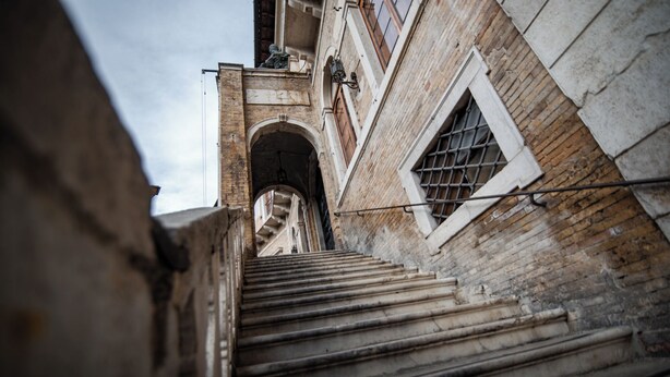 Eine Treppe führt zu einem Gebäude mit einer Ziegelverkleidung und Rundbogenfenstern.