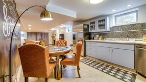 A modern kitchen with a dining area, featuring a large island, pendant lighting, and a checkered floor.