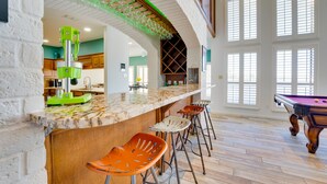 Un intérieur spacieux comprenant un bar, une table de billard et de hauts plafonds.