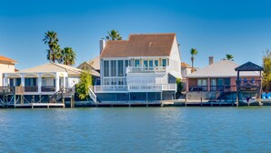 Une propriété située au bord de l’eau, avec une grande maison dotée d’un balcon, d’un quai et d’un bateau.