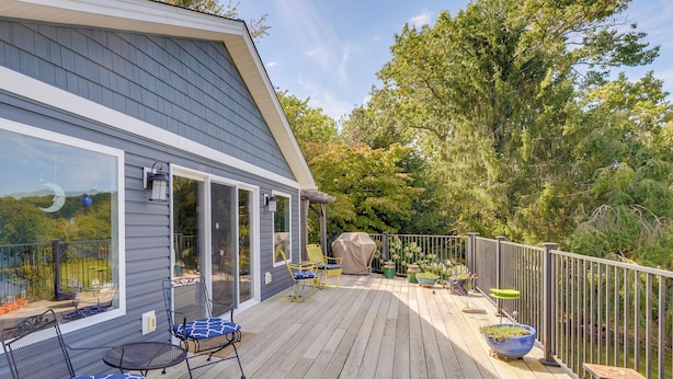 Eine Terrasse mit Gartenmöbeln, einem überdachten Sitzbereich und Blumentöpfen.