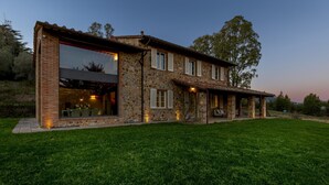 A two-story stone house with a large glass window and a covered patio area. - Villa Dada 10 Emma Villas (Rosignano Marittimo)