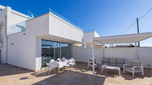 A modern outdoor patio with a dining table, chairs, and a sofa.