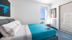 A modern bedroom with a large bed, a view of the sea through a window, and a painting on the wall. - Villa Ristola 6 Emma Villas (Castrignano del Capo)