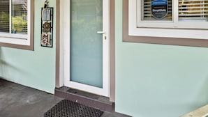 Entrada de un edificio con puerta de vidrio esmerilado, un letrero de seguridad y un escalón que lleva a la puerta.