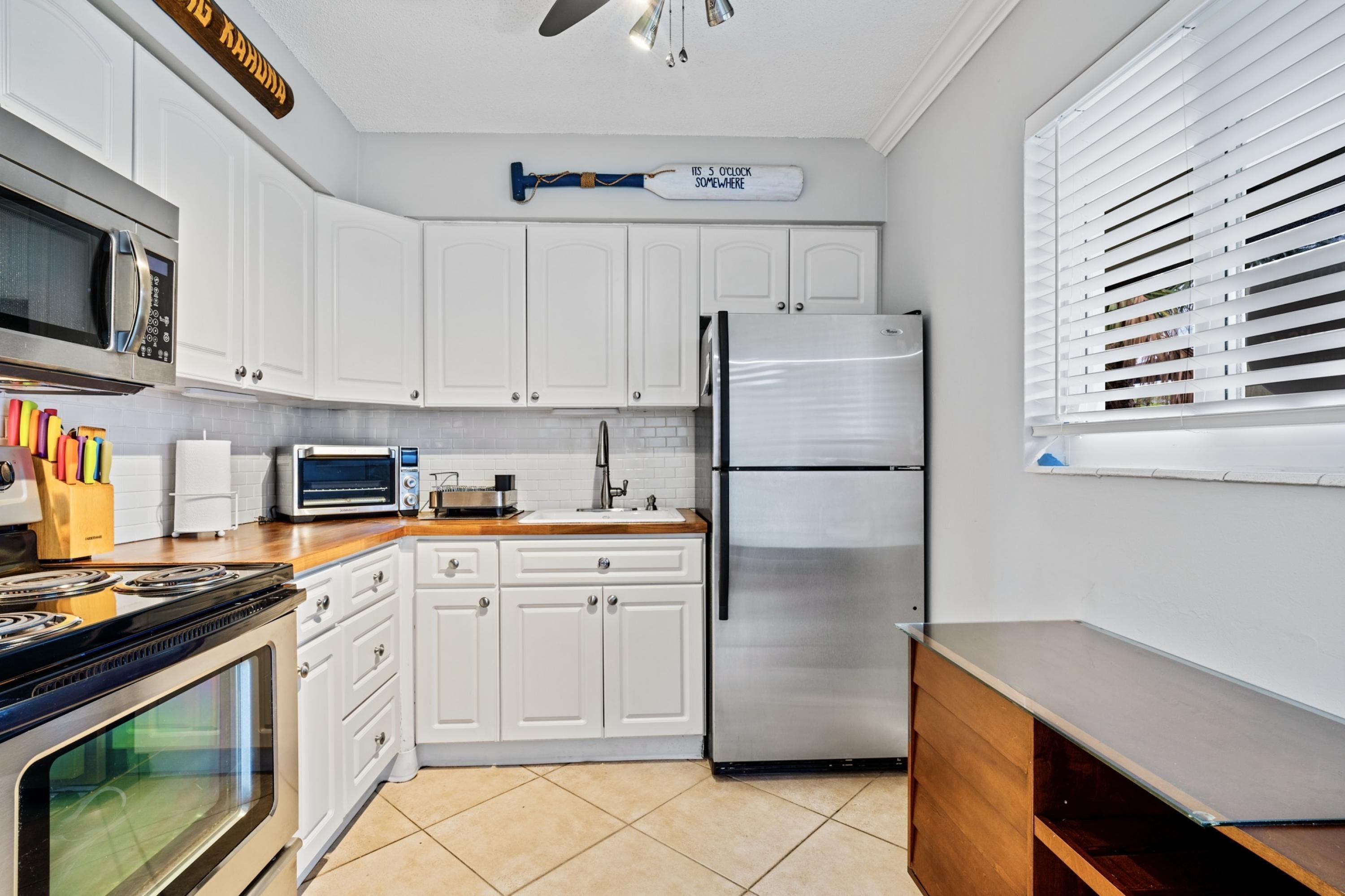 Una cocina moderna con gabinetes blancos, un refrigerador de acero inoxidable, un microondas y un tostador.