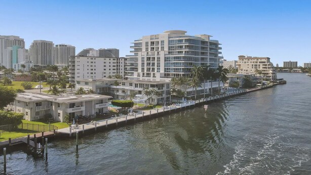 Een hotel aan het water met een modern design, meerdere balkons, een zwembad en uitzicht op het water.