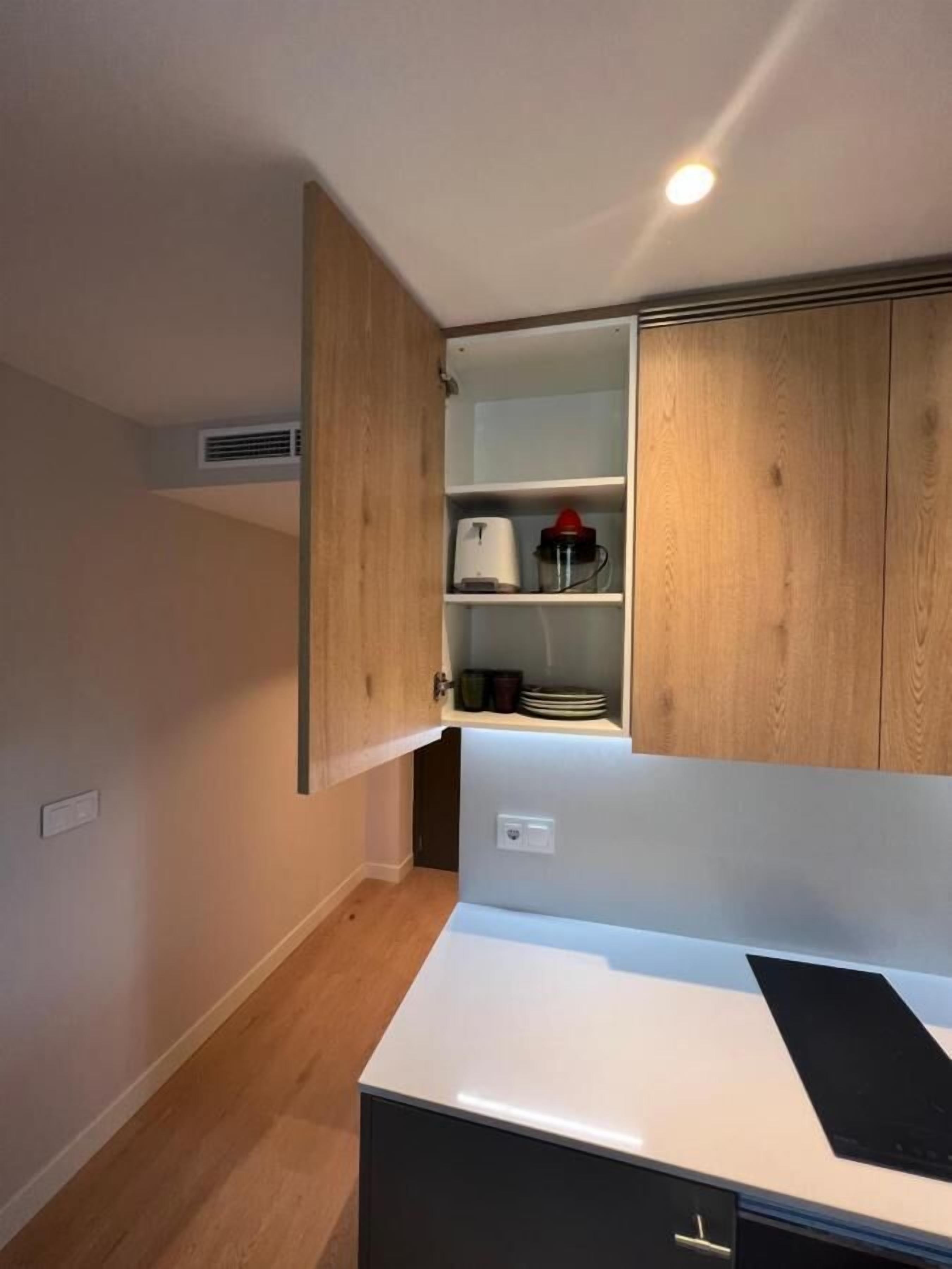 A compact kitchen with wooden cabinets, a white countertop, and a built-in stove.