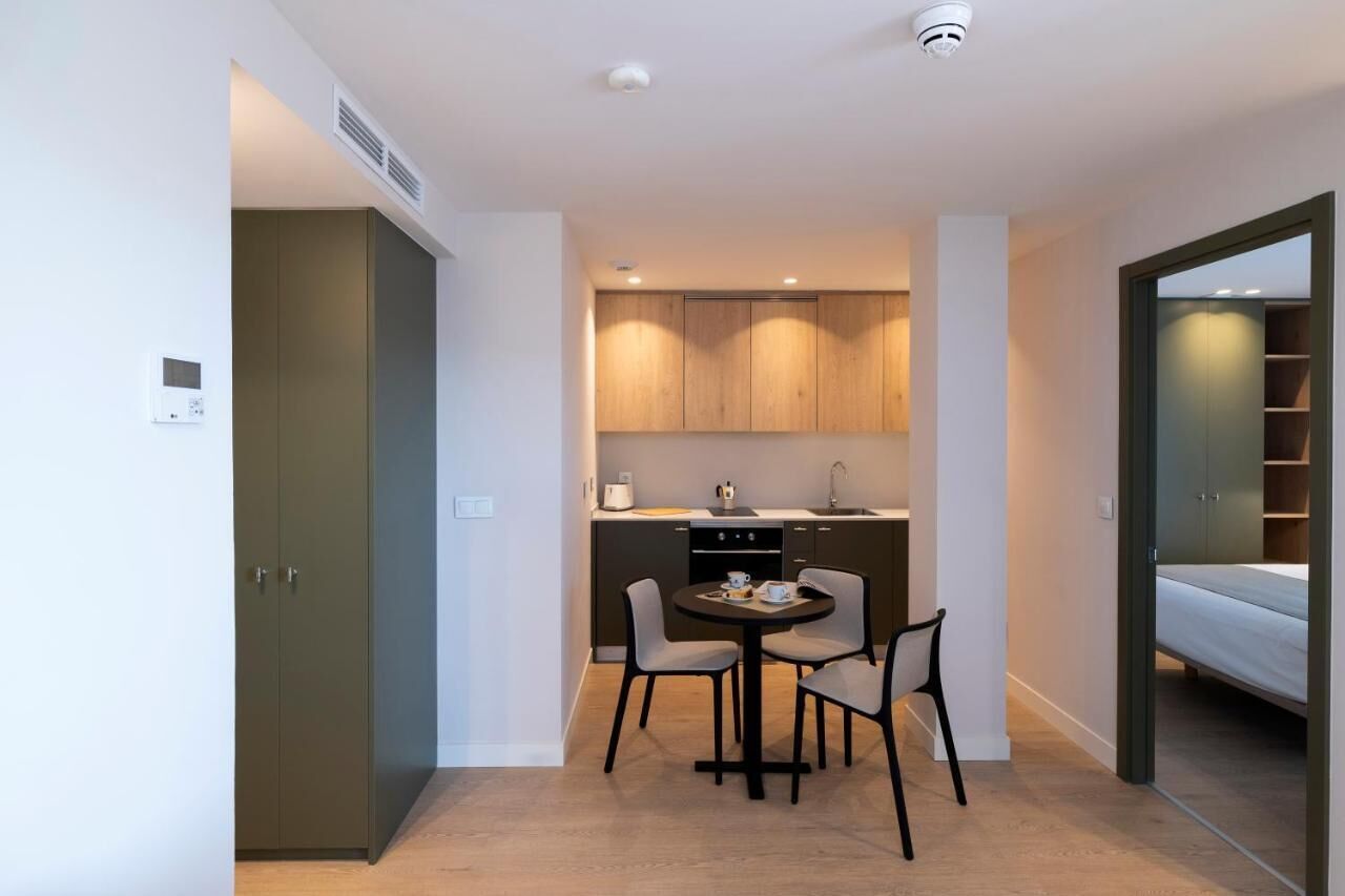 Un espacio habitable compacto con kitchenette, comedor para dos personas y cama en una habitación separada.