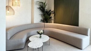 A modern living room with a curved grey sofa, two round white coffee tables, and hanging pendant lights. - Hotel H4 Cangas (Cangas)