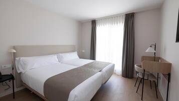 Una habitación de hotel con una cama grande, un escritorio y una silla.