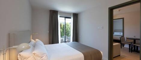 A modern hotel room with a large bed, a desk, and a balcony.