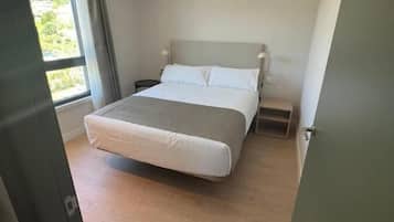 Ett sovrum med en säng, sängbord, ett fönster och en luftkonditioneringsanläggning som är monterad i taket.