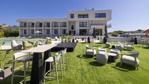 A modern hotel with a rooftop pool area featuring outdoor seating and a well-maintained lawn. - Hotel H4 Cangas (Cangas)
