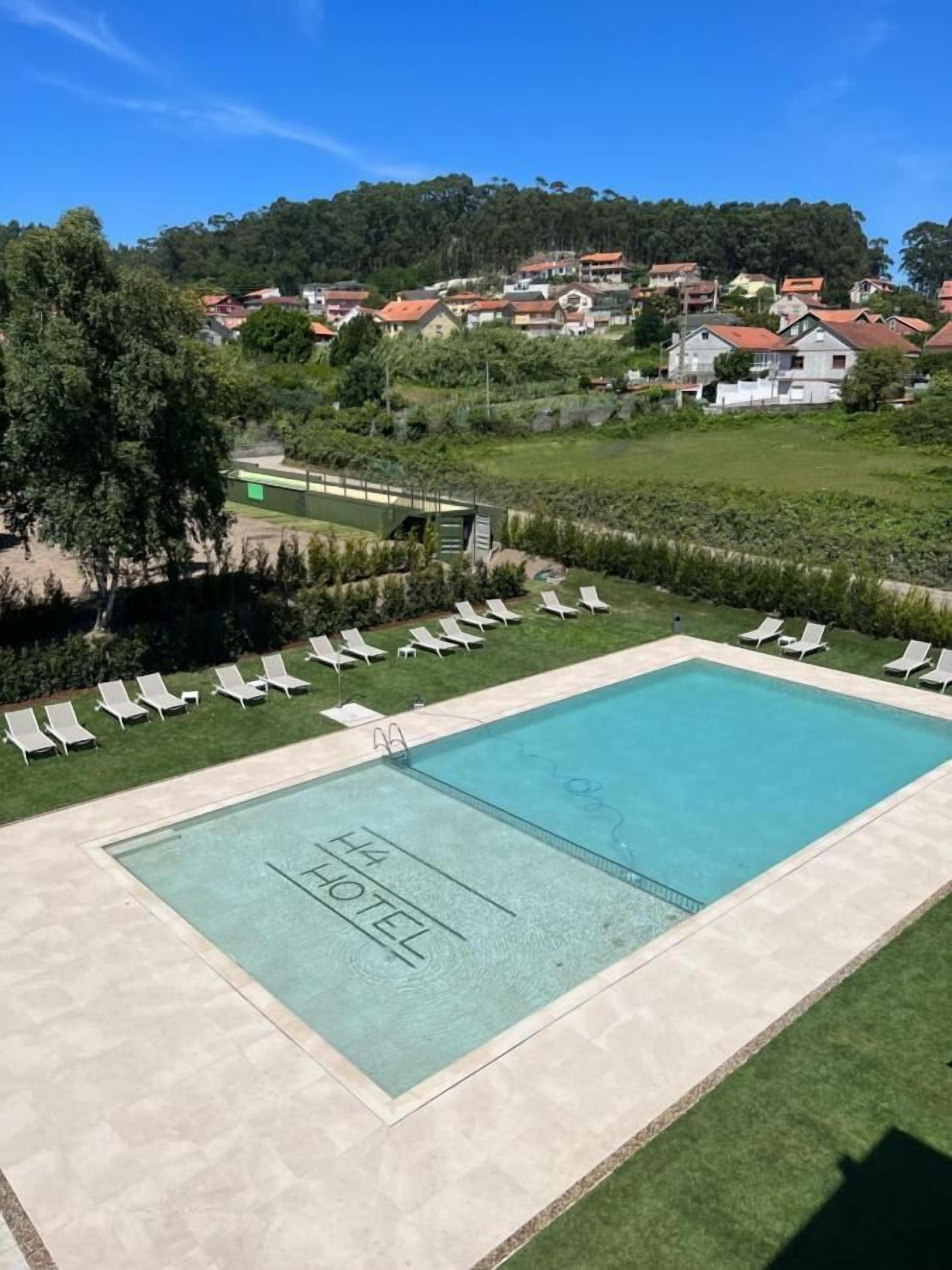 Zona d'una piscina d'hotel amb vista clara al paisatge circumdant, incloent un turó amb cases.