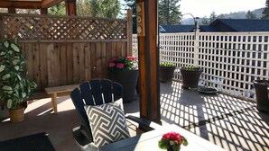 An outdoor patio with a wooden fence, a table with chairs, and potted plants.