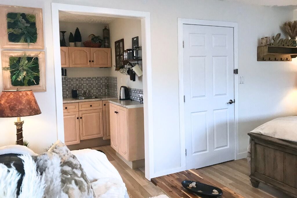 Een kleine keuken met houten kastjes, een koffiezetapparaat en een betegelde spatwand.