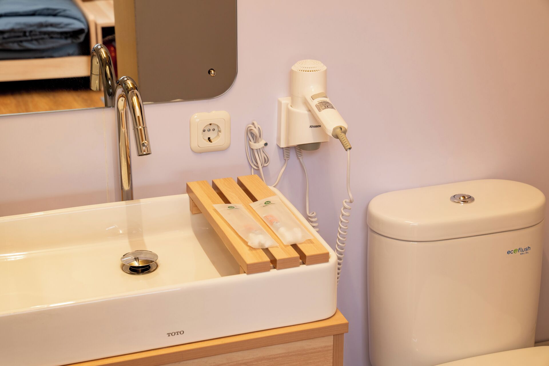 A bathroom with a white sink, a mirror, a hairdryer, and a toilet.