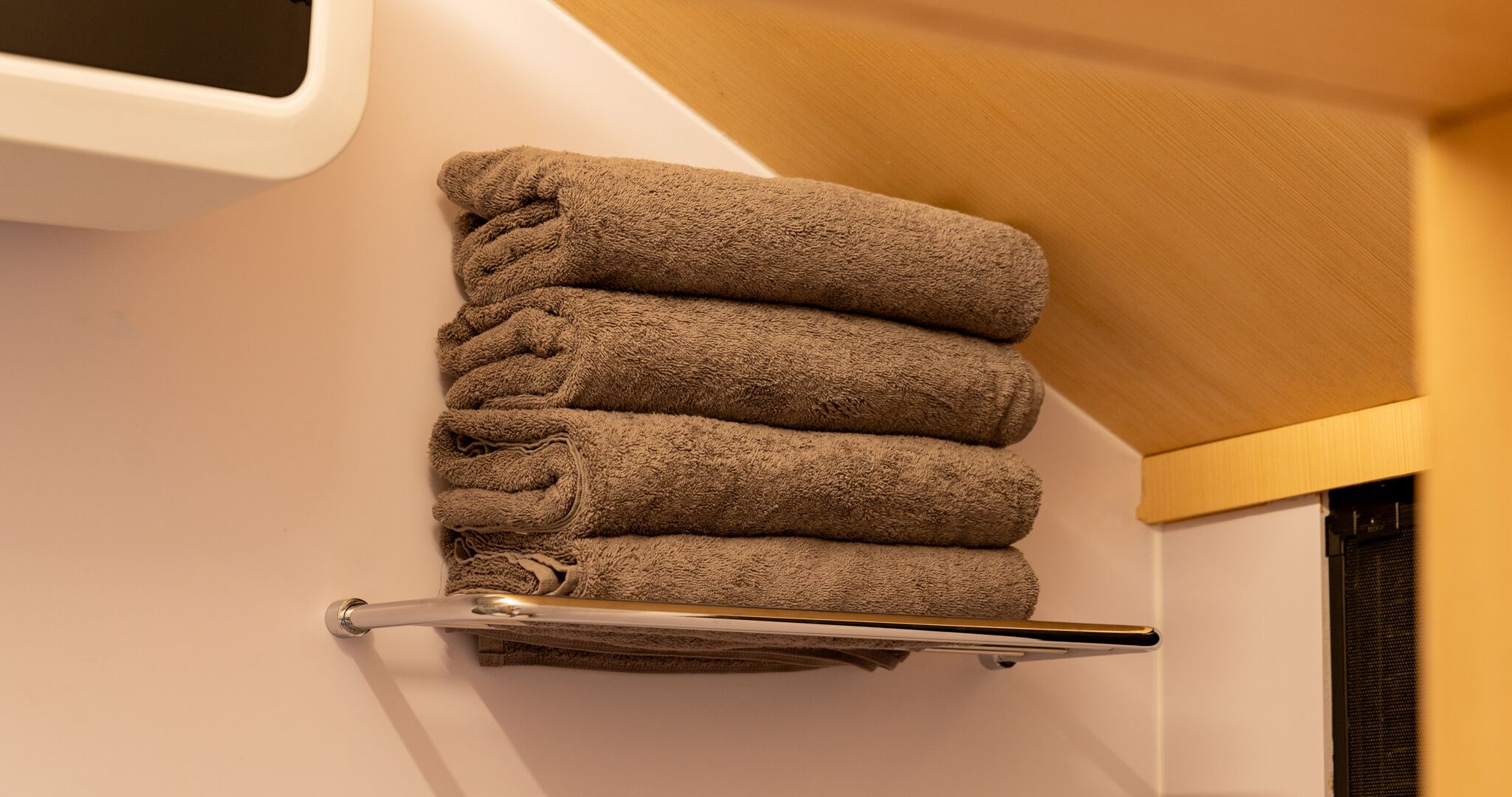 Ein Badezimmer mit einem Handtuchhalter, der vier gefaltete Handtücher trägt.