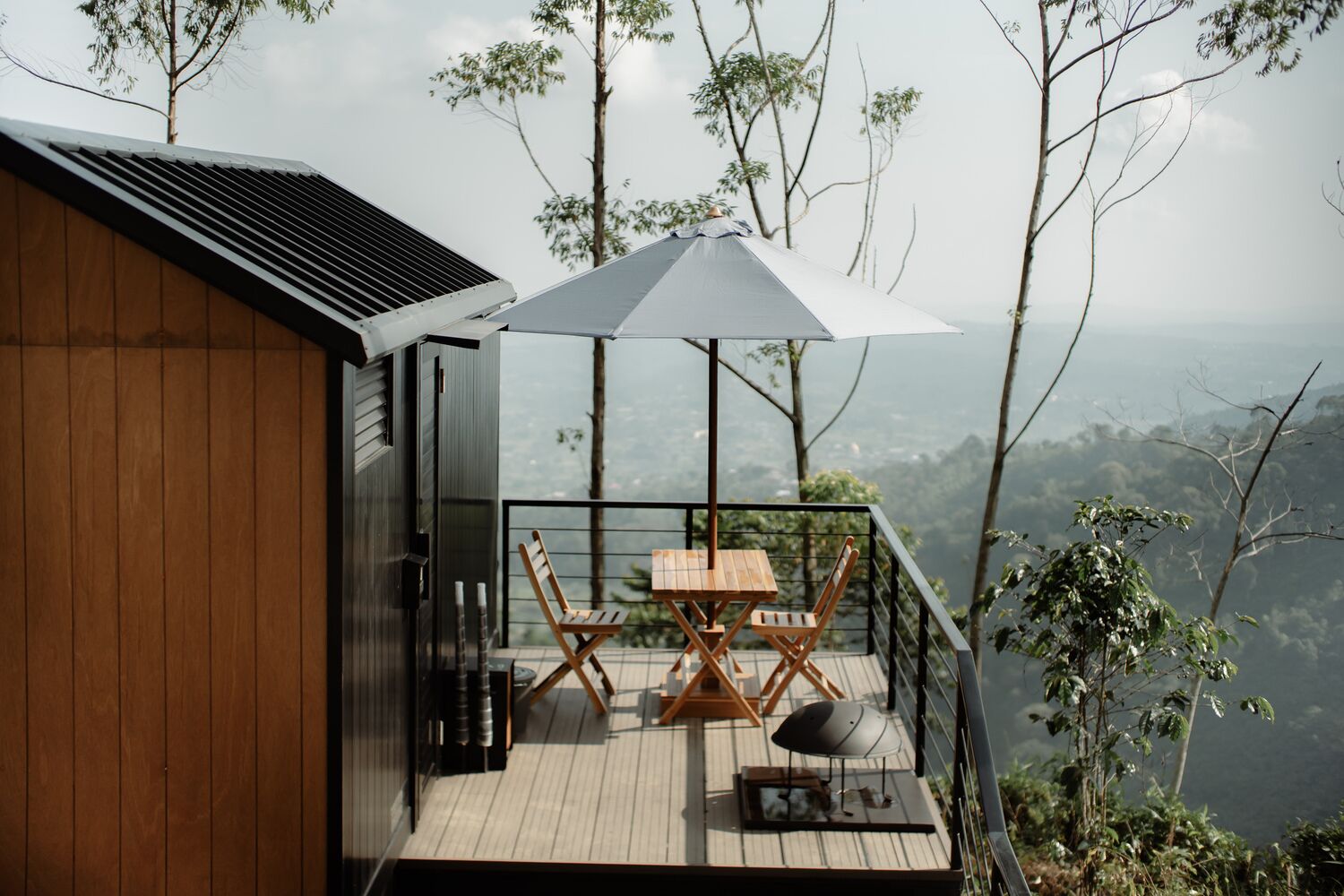A wooden deck with a table and chairs, a barbecue grill, and a large umbrella.