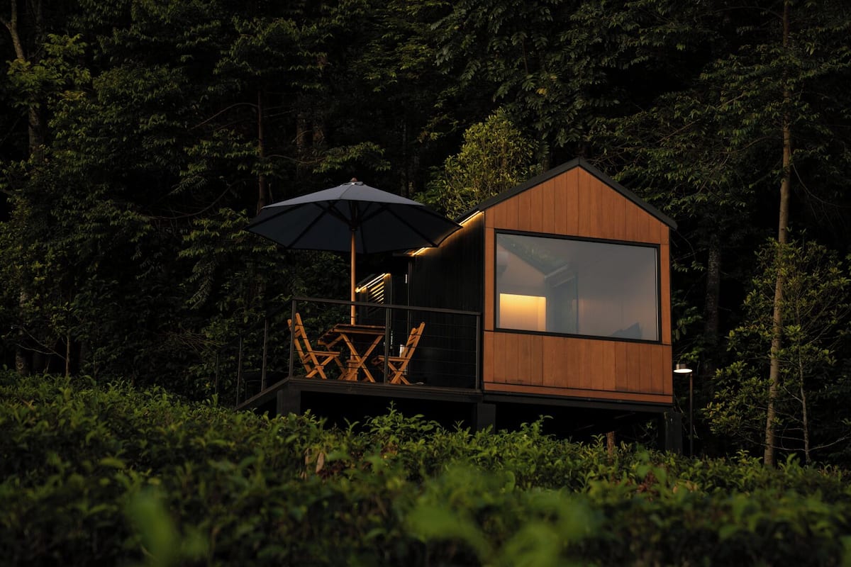 A wooden cabin with a balcony, a table, and an umbrella.