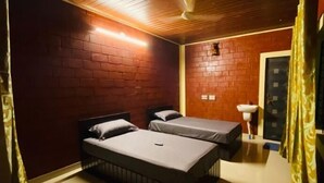 Una habitación con dos camas individuales, un lavamanos pequeño y un ventilador de techo.
