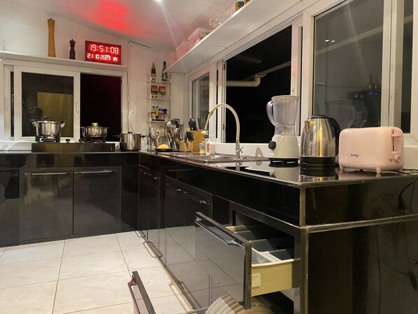 A modern kitchen with black cabinets, a stainless steel countertop, a sink, a toaster, and a blender.