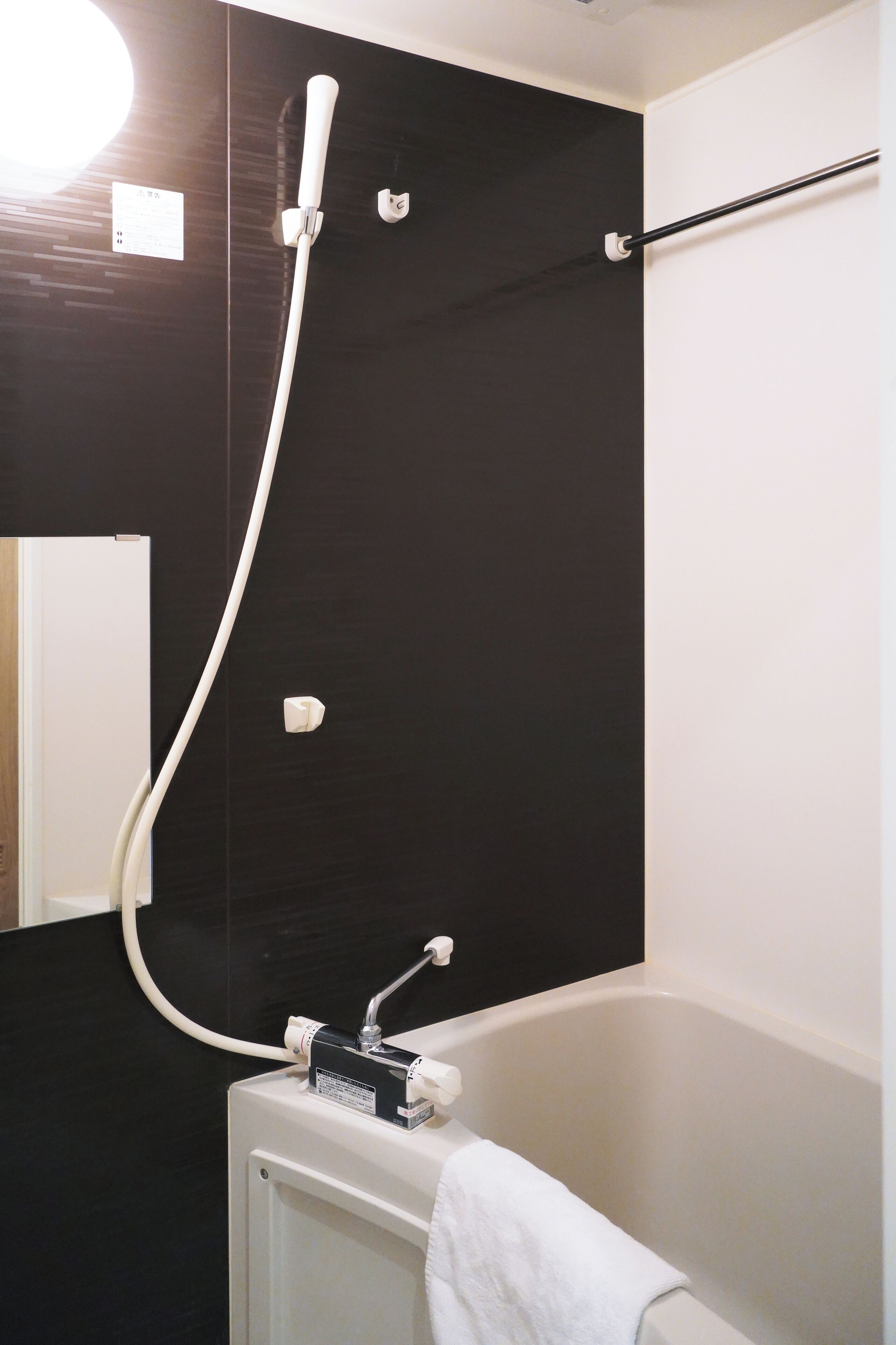 Een badkamer met een bad, een douche en een handdoekhouder.
